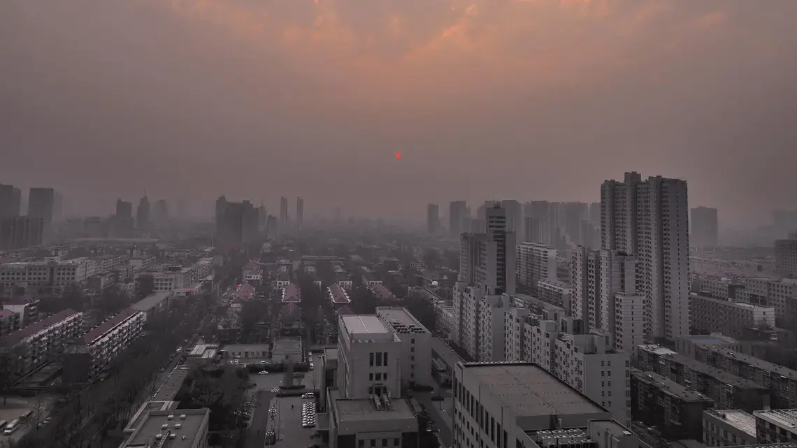 A spring sunrise barely pierces a thick layer of pollution over Shijiazhuang. Image by Larry C. Price. China, 2018.