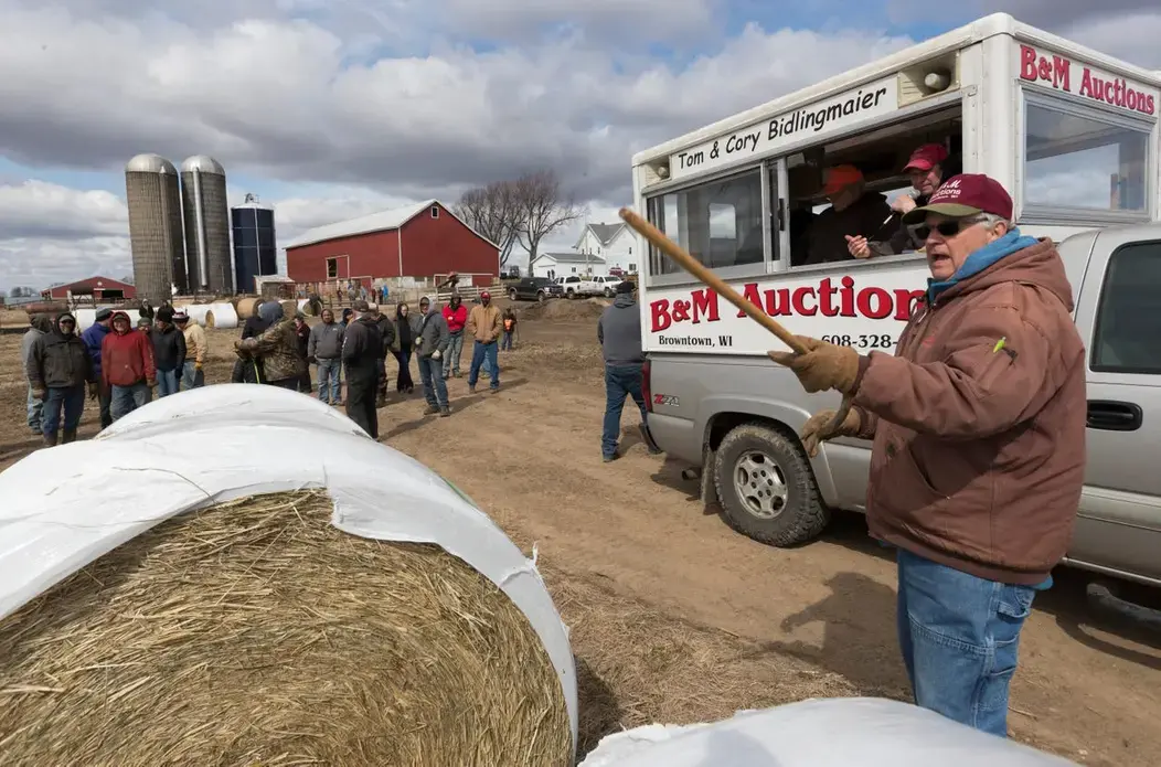 Tom Bidlingmaier points out a bidder on hay during an auction. Image by Mark Hoffman. United States, 2019.