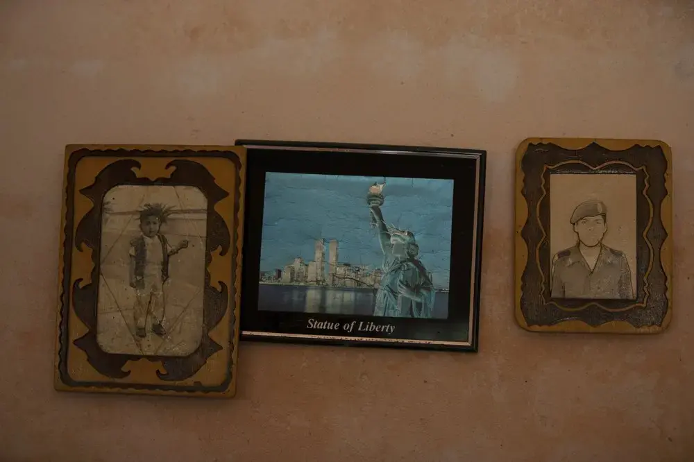 Photographs of Jorge Vazquez, left, and his brother Orlando Vazquez flank an image of the Statue of Liberty in New York, inside the home of their mother Catalina Vazquez in San Jeronimo Xayacatlan, Mexico, Thursday, June 25, 2020. Image by Fernando Llano/AP Photo. Mexico, 2020.<br />

