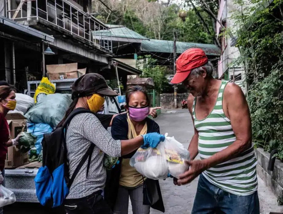 Volunteer health worker Analyn Martinez (left) and Fatima distribute relief goods to the community. Image by Xyza Bacani. Philippines, 2020.