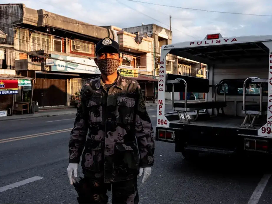 Police officer Emmanuel Ventura works a quarantine checkpoint. Image by Xyza Bacani. Philippines, 2020.