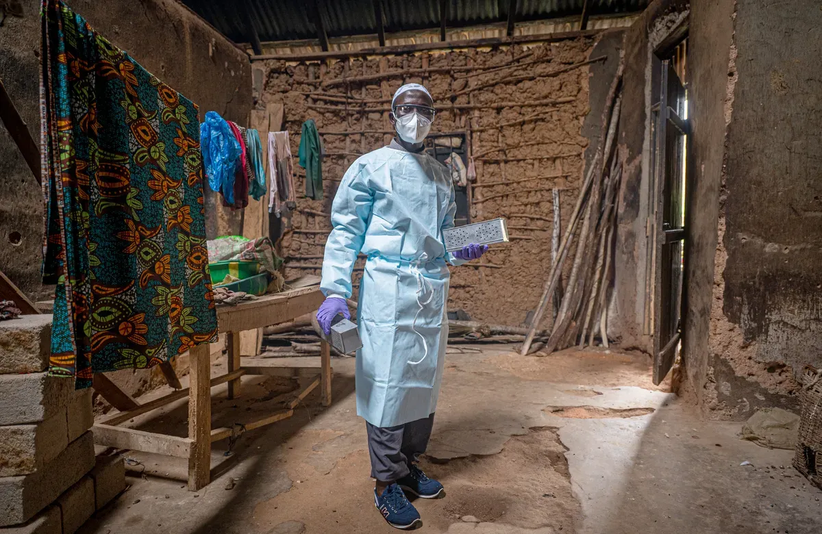 a man in scrubs wearing a mask stands in a courtyard