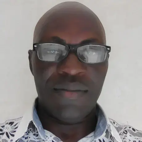 A man wears glasses and a white shirt, he smiles at the camera.