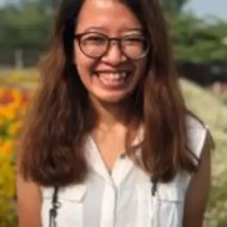 A woman with glasses and wearing a white shirt smiles into the camera.