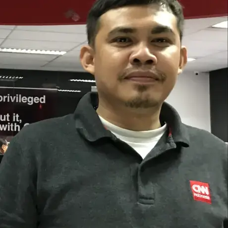 A person wears a black shirt with a red patch logo.