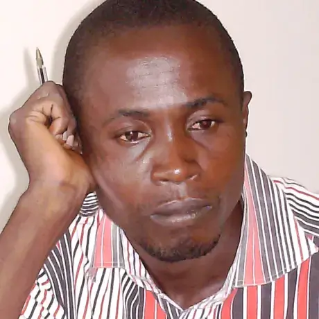 john ndinga (1).jpg A person wears a red and white patterned shirt. The person is also holding a pen.