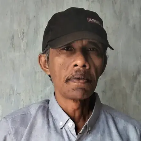 A man wears a cap and a blue shirt.