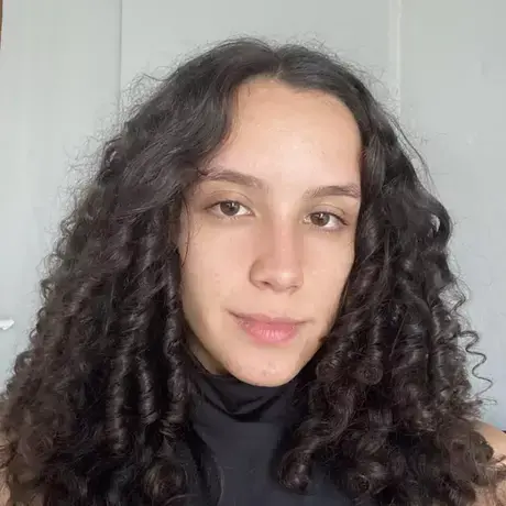 a woman with curly hair looks into the camera