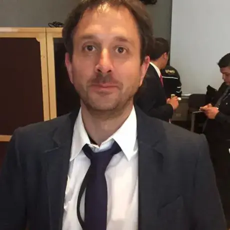 A headshot of a man in a suit and tie with short dark hair