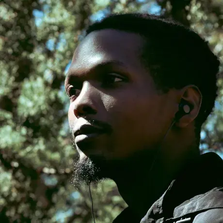 A profile portrait of a man with dark skin and short dark hair