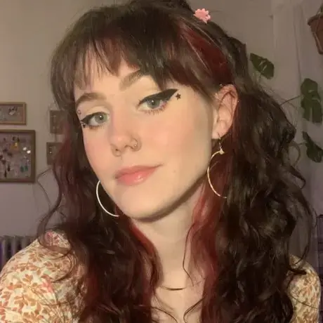 A woman with light skin and dark hair looks at the camera