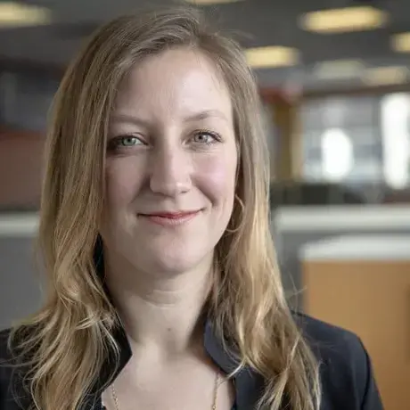 A woman with light skin and blonde hair smiles at the camera