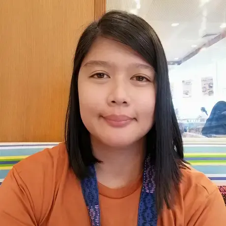 A woman with medium length dark hair wearing an orange shirt
