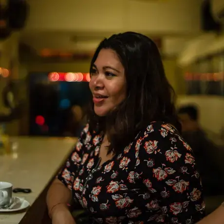 A woman with long hair wearing a floral dress sits at a restaurant counter