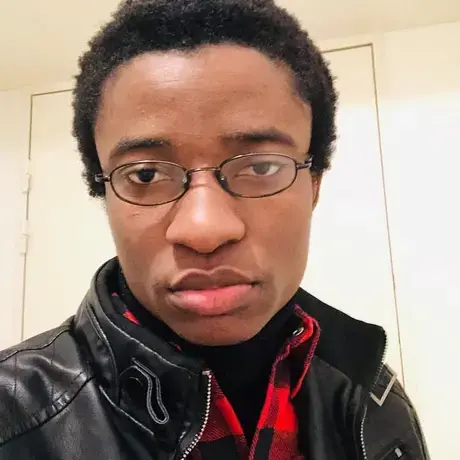 Will looks into the camera wearing a black jacket and red scarf.