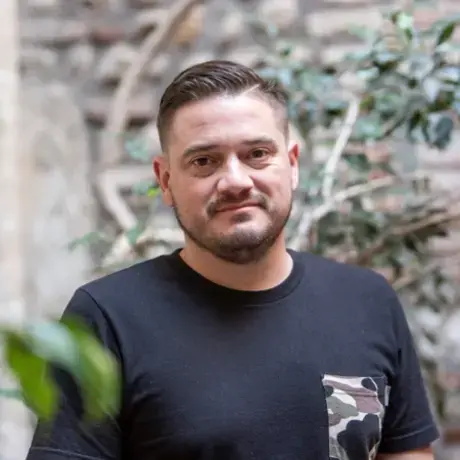 A man wearing a black shirt stands among plant vines