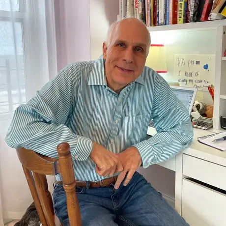 a man wearing a blue striped button down sitting at a desk