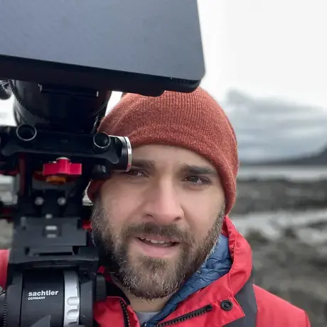 Man wearing a red coat and red hat holding a large camera