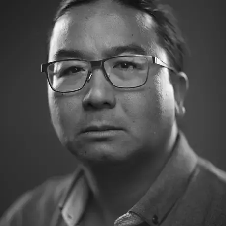 Black and white headshot of a man with glasses wearing a button down shirt