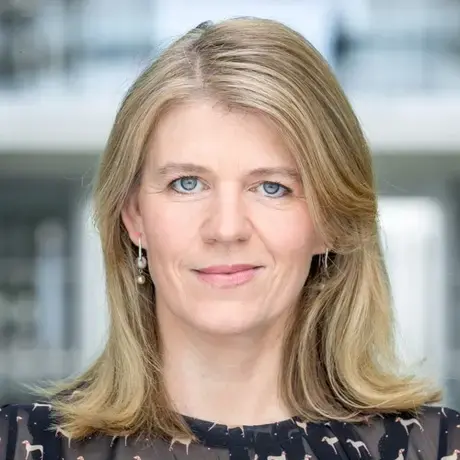 A woman with shoulder-length blonde hair wears a navy patterned blouse