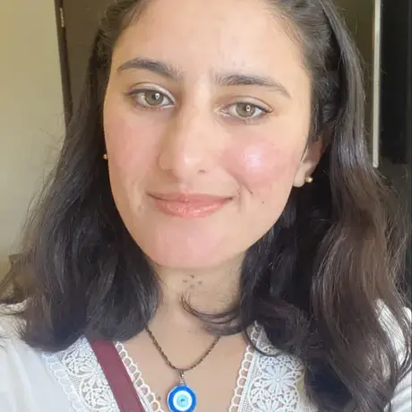 A woman with shoulder-length dark hair wearing a white blouse