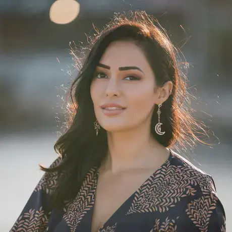 A woman with long dark hair wearing drop earrings and a black blouse