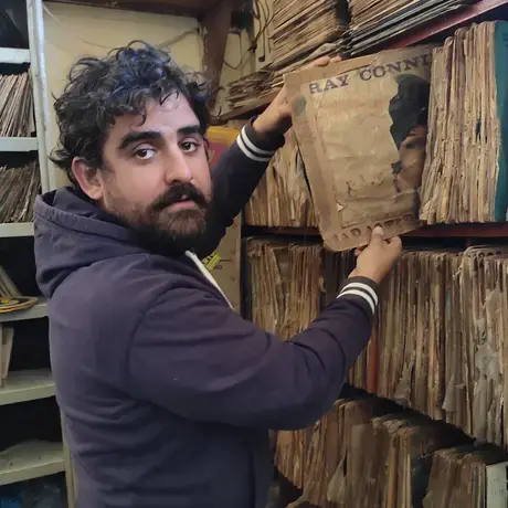 Cesar is putting an old book back into the shelf.