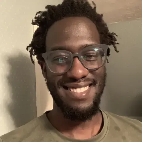 headshot of Carey wearing glasses and a green t-shirt