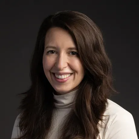 Headshot of woman with long brown hair in a white turtleneck