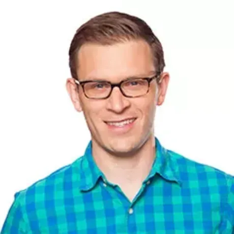 Headshot of man in glasses in blue checkered shirt against white background