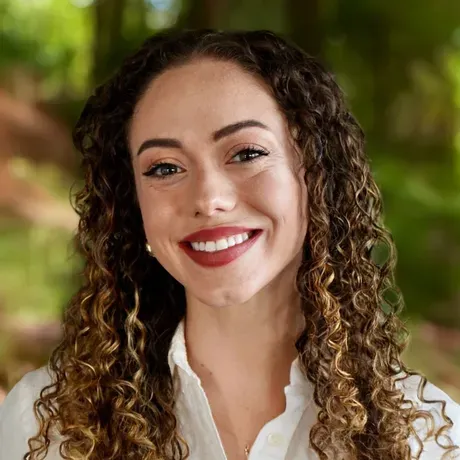 A headshot of a young woman with curly hair