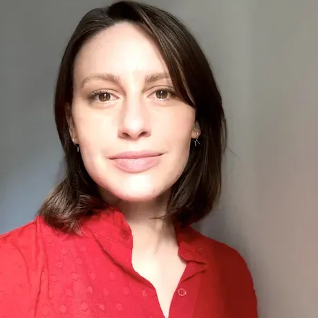 A headshot of a young woman with shoulder length hair in a red shirt