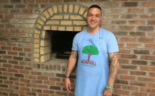 Bradley Johnson, a volunteer for Hemphill Catering Co. with new brick oven at Hemphill community center. Image by Richie Davis. United States, 2018.
