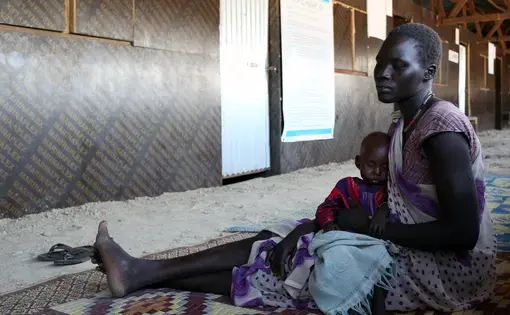 Nyabany and her daughter wait at a clinic at the U.N. base in Bentiu, South Sudan, on Dec. 18, 2016. Eight-month-old Nyadholi is suffering from severe acute malnutrition. Image by Cassandra Vinograd. South Sudan, 2016.