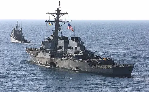 The USS Cole (DDG 67) is towed away from the port city of Aden, Yemen, into open sea by the Military Sealift Command ocean-going tug USNS Catawba (T-ATF 168) on Oct. 29. Image by Sgt. Don L. Maes, U.S. Marine Corps. Yemen, 2000. (Public Domain)