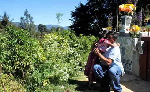 Gilberto Gomez-Gonzales hugs his youngest daughter during a visit to the cemetery where his eldest daughter, Claudia Gomez-Gonzalez, was laid to rest after she was killed by a U.S. Border Patrol agent in May and repatriated to her hometown of San Juan, Quetzaltenango, Guatemala. Image by Kristian Hernandez. Guatemala, 2018. Gilberto Gomez-Gonzales hugs his youngest daughter during a visit to the cemetery where his eldest daughter, Claudia Gomez-Gonzalez, was laid to rest after she was killed by a U.S. Border Patrol agent in May and repatriated to her hometown of San Juan, Quetzaltenango, Guatemala. Image by Kristian Hernandez. Guatemala, 2018.