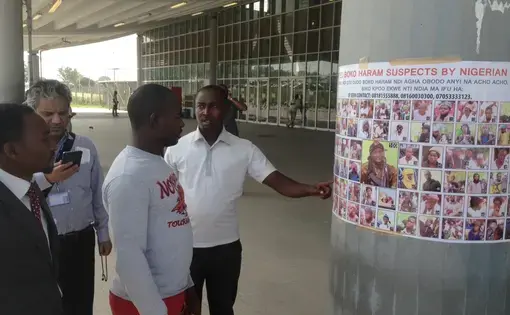 Travelers examine a most wanted poster featuring Boko Haram suspects at an airport near the Nigerian capital. Image by Jason Motlagh. November 2015.