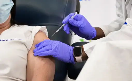 A medical worker administers the Pfizer-BioNTech COVID-19 vaccine to an ICU nurse at the Long Island Jewish Medical Center. Image by noamgalai / Shutterstock. United States, 2020.
