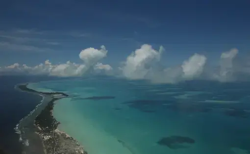 More than half of Kiribati’s 110,000 people live on the capital island of Tarawa. It’s a heavily developed string of islets connected by causeways in various states of disrepair. The deep blue Pacific Ocean sits on one side, the shallow aquamarine lagoon on the other. From any place on the atoll, the water is always a short walk away. Image by Kenneth R. Weiss. Kiribati, 2014. Media file: img_8504.jpg