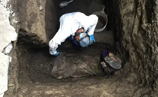 Forensic criminologist Ticas Israel brushes the body of an unidentified man killed by gang members and buried in a hidden grave in Ilopango. Image by Jason Motlagh. El Salvador, 2016.