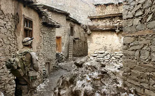 A soldier walks through an alley in the vicinity of Methar Lam. Image by Cpl. James L. Yarboro. Afghanistan, 2005.