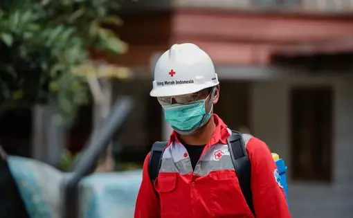 A Red Cross volunteer working to prevent the spread of COVID-19. Image by rizaazhari/shutterstock. Indonesia, 2020.