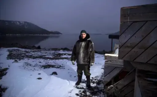 Karl Michelin poses for a portrait at the water's edge of Lake Melville in Rigolet wearing a dickie made of seal skin from a seal he hunted from the bay on Nov. 13, 2019. Image by Michael G. Seamans. Canada, 2019.