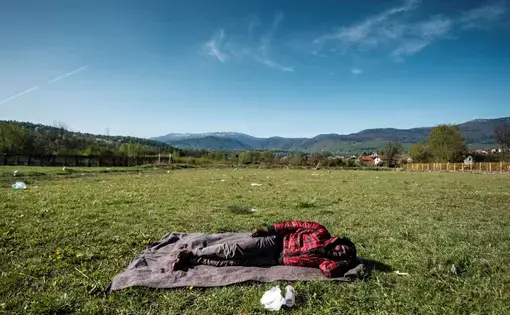 Bihać, Bosnia-Herzegovina: A young Pakistani is seen sleeping rought on the grass of the football pitch in Bihac. Bihac and the north-western part of the country is taking the brunt of the escalating crisis. Being in proximity of the border with Croatia it is a logical route for the people on the move. Image by Ziyah Gafic. Bosnia-Herzegovina, 2020.