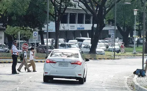 At the Ateneo de Manila University in Quezon City, security guards are trained to help students cross the street safely. Image by Dinna Louise C. Dayao. Philippines, 2019.