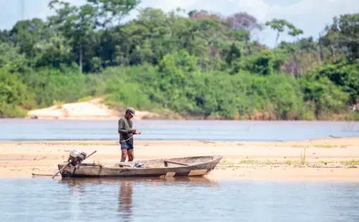 A man from a traditional Indigenous population preparing his boat and tools on the Araguaia river waters in Santa Terezinha, Mato Grosso. Image by JH Bispo/Shutterstock. Brazil, 2019.