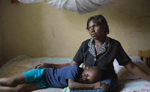 Christine Namatovu and her son Andrew bring solace to each other in the house Namatovu’s in-laws tried to seize when her husband died. Pushing widows off their property is common practice in this region; Namatovu, with the help of lawyers, fought back. Image by Amy Toensing. Uganda, 2016.