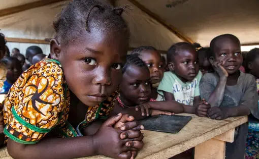 Children are taught in a makeshift classroom at a camp in Kaga Bandoro that provides refuge for thousands of Central African families displaced by conflict. Image by Jack Losh. Central African Republic, 2019.