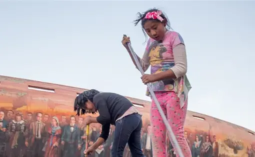 An 8-year-old child, right, and her friend sweep the pavement outside the Jaime Laredo Outdoor Theater in La Paz. Children are allowed to work for themselves or their families at age 10 in Bolivia. At 12, they can work for others. Image by Tracey Eaton. Bolivia, 2018.