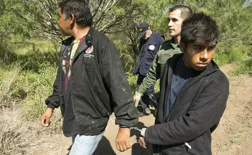 Border Patrol Agent Roberto Rodriguez escorts two Mexican nationals apprehended near the Texas-Mexico border on Oct. 12, 2017. Image by Marjorie Kamyd. United States, 2017.